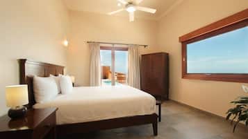 Un dormitorio con cama, mesita de noche, lámpara, ventilador de techo, ventana y vistas a un balcón.