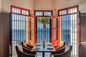 A dining area with a table set for four, overlooking a body of water through a window with metal bars. - Casa Lucila Mazatlan Curamoria Collection (Mazatlán)