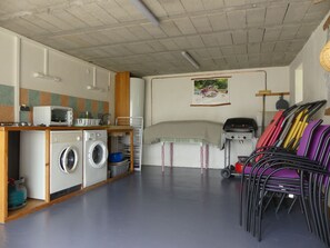 A compact kitchen with a washing machine, a microwave, and a small dining area with chairs. - Renovated farmhouse, panoramic view - guests (Vorey)