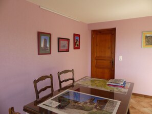 A dining area with a glass-top table displaying a map and a framed picture on the wall. - Renovated farmhouse, panoramic view - guests (Vorey)