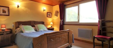 Une chambre à coucher avec un lit en bois, des lampes de chevet, une fenêtre avec des rideaux et un radiateur.