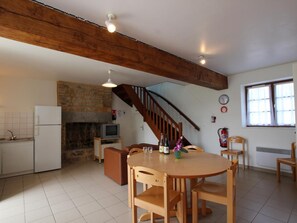 Eine geräumige Küche mit Steinwand, einer Holztreppe und einem Essbereich mit Holztischen und -stühlen.