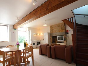 Eine geräumige Küche mit Steinwand, ein Essbereich mit Holzmöbeln und eine Treppe.