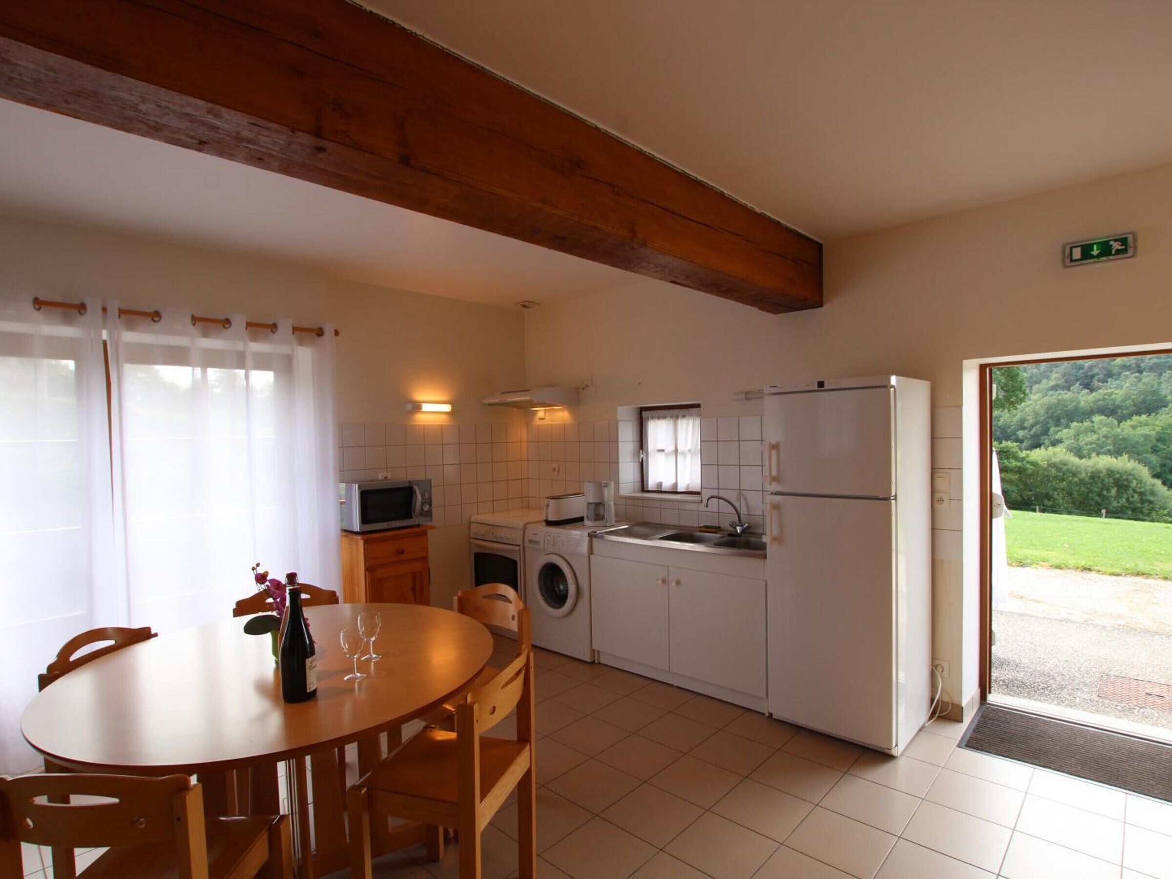 A kitchen with a dining table, chairs, a washing machine, a microwave, and a refrigerator.