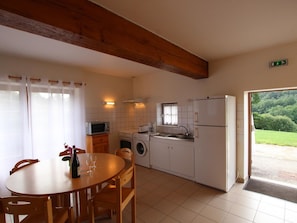 Eine Küche mit Esstisch, Stühlen, einer Waschmaschine, einer Mikrowelle und einem Kühlschrank.