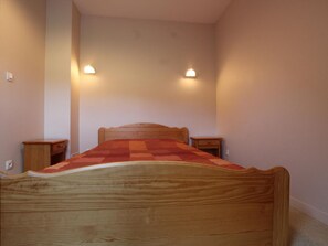 A bedroom with a wooden bed, two bedside tables, and wall-mounted lamps. - Charming house, parking, pets welcome - 5 guests (Saint-Georges-de-Rouelley)