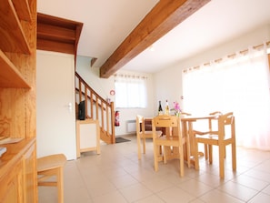 A dining area with wooden furniture, a staircase, and a window with curtains. - Charming house, parking, pets welcome - 5 guests (Saint-Georges-de-Rouelley)