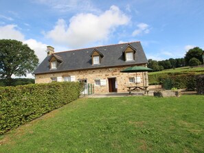 A stone house with a sloped roof, a wooden door, and a green umbrella. - Charming house, parking, pets welcome - 5 guests (Saint-Georges-de-Rouelley)