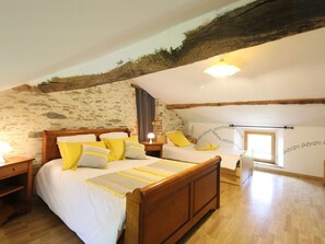 A bedroom with a sloped ceiling, a wooden bed, and a nightstand. - Peaceful cottage with garden and games - 7 guests (Lys-Haut-Layon)