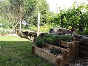 Ein Garten mit einem hölzernen Pflanzkasten, einem rustikalen Fass und einem Holzpfosten.