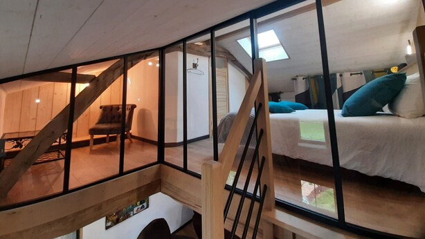 Ein Schlafzimmer im Loft-Stil mit einem Bett, einem Sessel und einer Treppe.