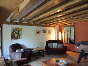 A spacious living area with wooden beams, a sofa, armchairs, and a coffee table. - Peaceful cottage with garden and games - 7 guests (Lys-Haut-Layon)
