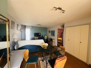 Une chambre d’hôtel de taille réduite, comprenant un lit, un bureau, une chaise, une télévision et une armoire.