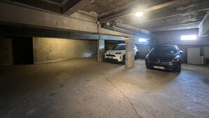 Parcheggio sotterraneo su più livelli con pavimenti e pareti in cemento, due auto parcheggiate e una singola luce al soffitto.