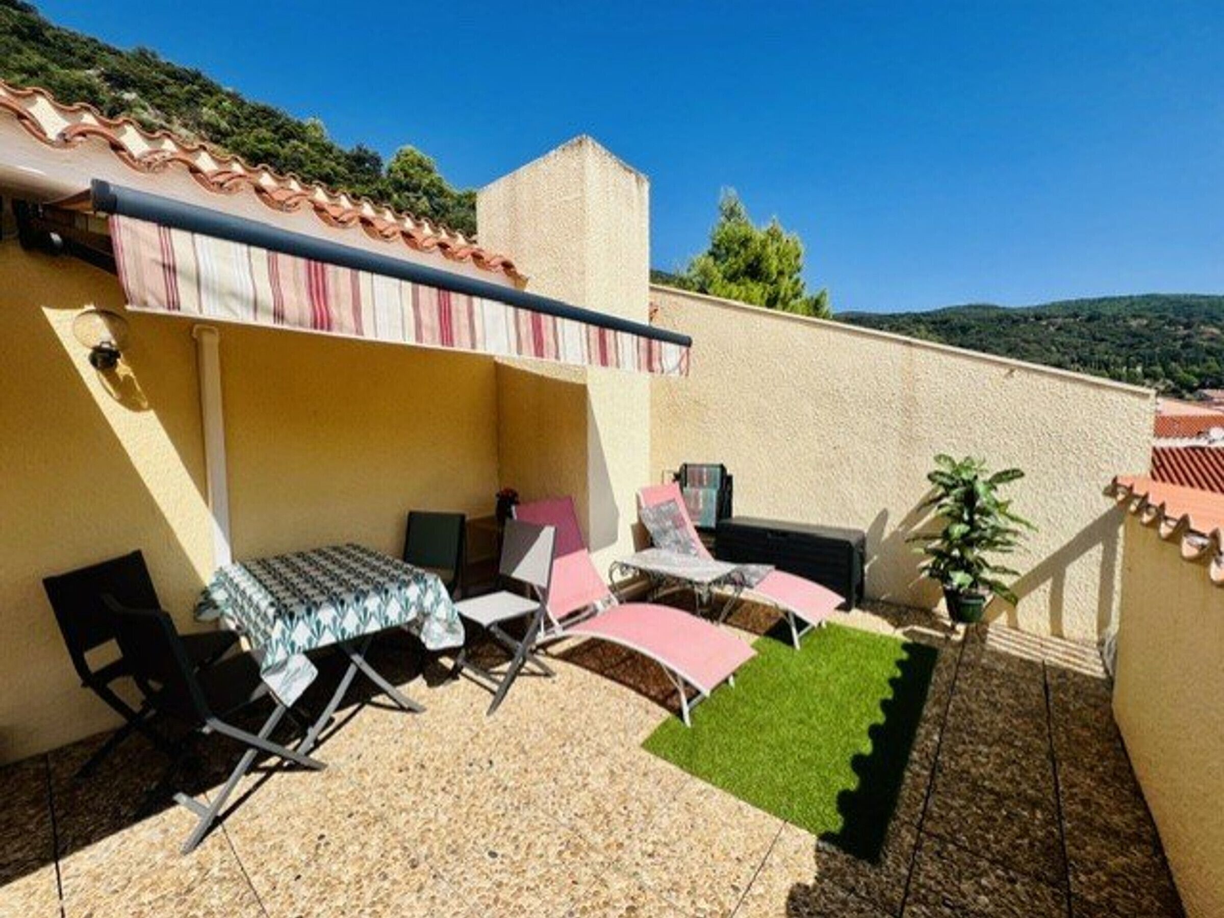 Un espace patio aménagé avec une table et des chaises, un petit jardin et une vue sur le paysage environnant.