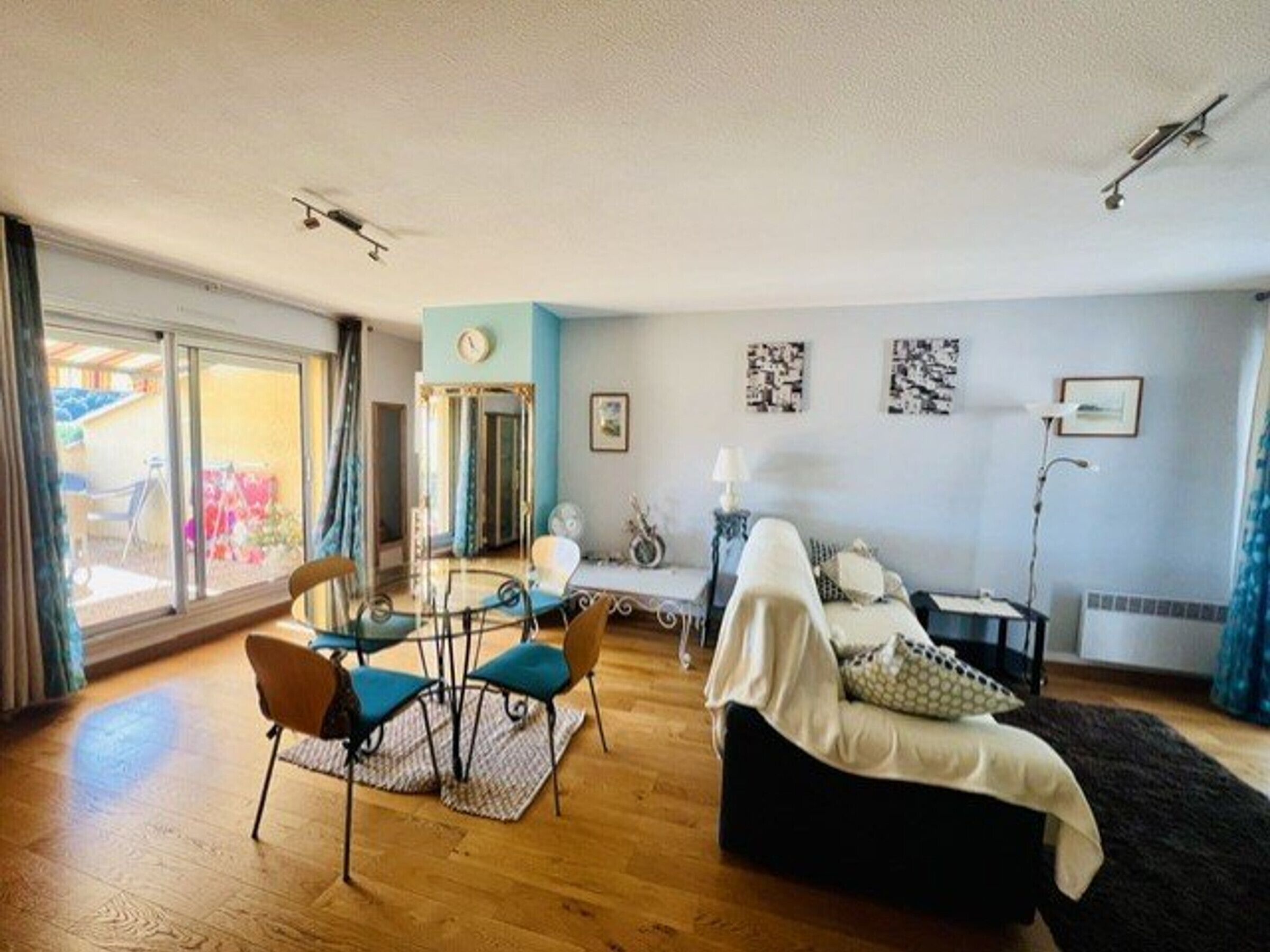 Ein Wohnzimmer mit einer Couch, einem Esstisch mit Stühlen, einer Lampe und Bildern an der Wand.