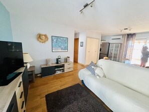 Ein modernes Wohnzimmer mit Flachbildfernseher, einer Couch, einem Couchtisch und einem Kamin.