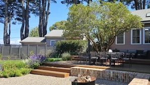 Un patio trasero con un brasero, mobiliario exterior y una terraza de madera.