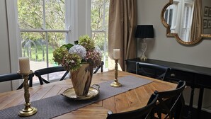 Una mesa de comedor con un jarrón de flores, velas y un espejo en la pared.