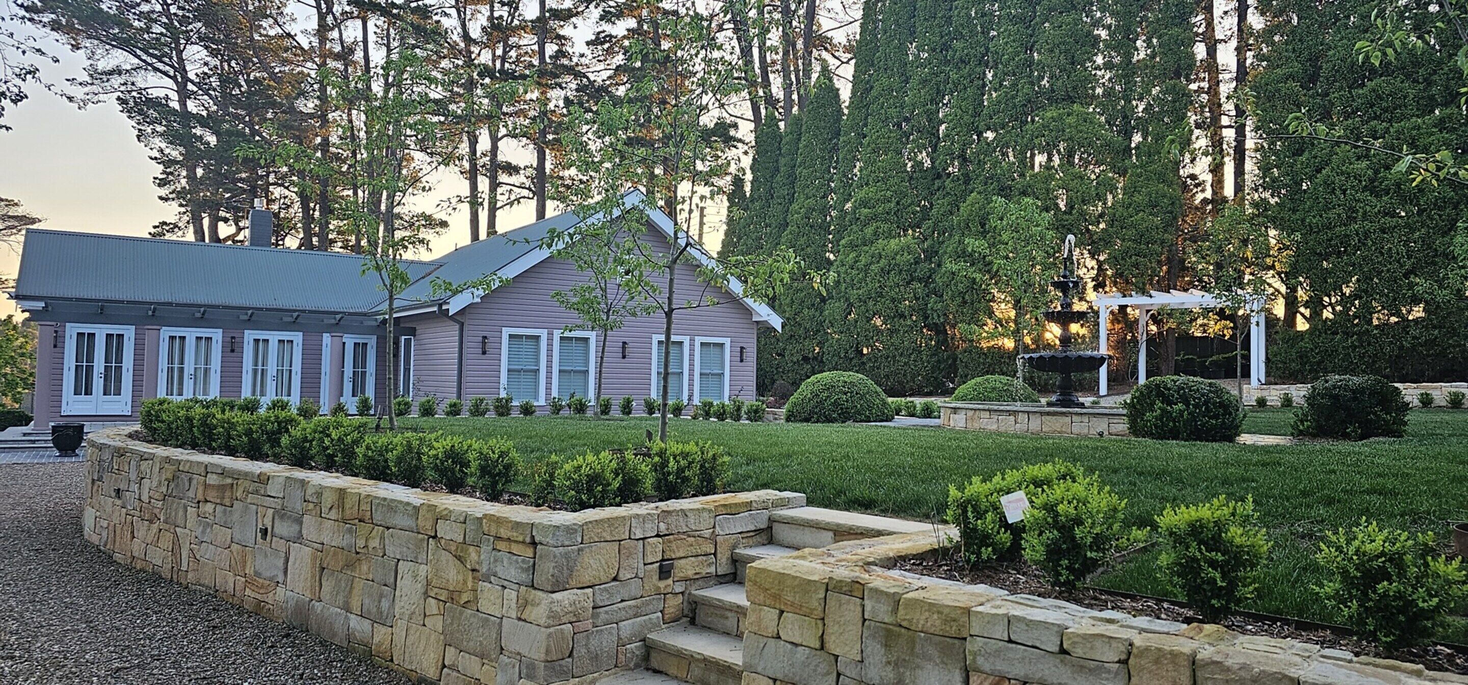 A two-story house with a stone retaining wall and a well-maintained garden.