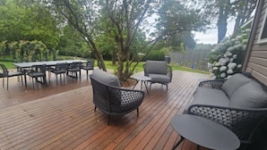 Una terraza al aire libre con una mesa y sillas para comer, un sofá y una planta en maceta.