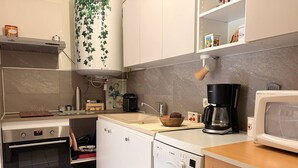 Kompakti keittiö, jossa on Bosch-astianpesukone, kahvinkeitin ja mikroaaltouuni.
