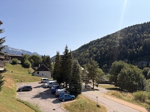 Un espace de stationnement avec plusieurs voitures, un petit bâtiment et un paysage montagneux en arrière-plan.