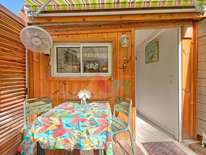 Eine Holzhütte mit Tisch, Stühlen, einem Ventilator und einem Fenster.