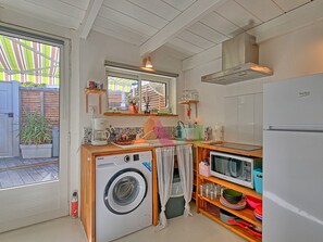 A compact kitchen with a washing machine, a microwave, and a refrigerator. - Ideal studio near beach, AC & parking (Saint-Martin)