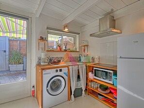 Eine kleine Küche mit Waschmaschine, Mikrowelle und Kühlschrank.