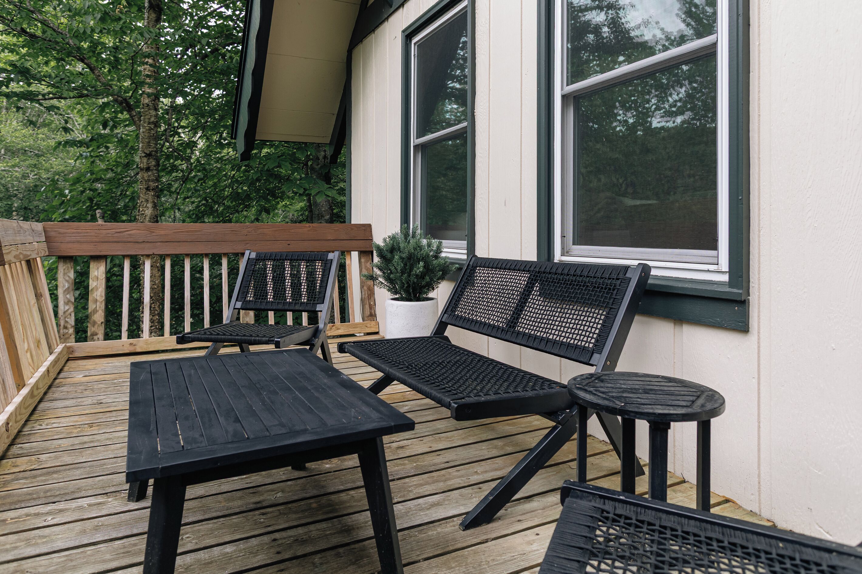 Eine Holzterrasse mit Gartenmöbeln, darunter ein Tisch und Stühle, sowie einem Blumentopf.