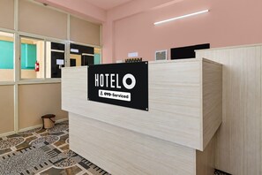 Ein Hotelrezeptionsschalter mit einem Schild, das angibt, dass er von OYO verwaltet wird.