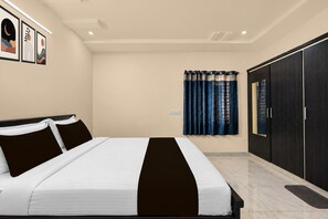 Ein Schlafzimmer mit einem Bett, einem Kleiderschrank und einem Fenster mit Vorhängen.