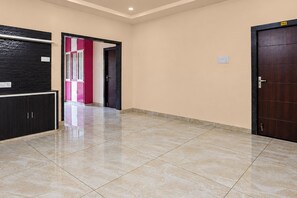 Un pasillo con piso de baldosas, un mueble negro, una puerta rosa y una puerta de madera.