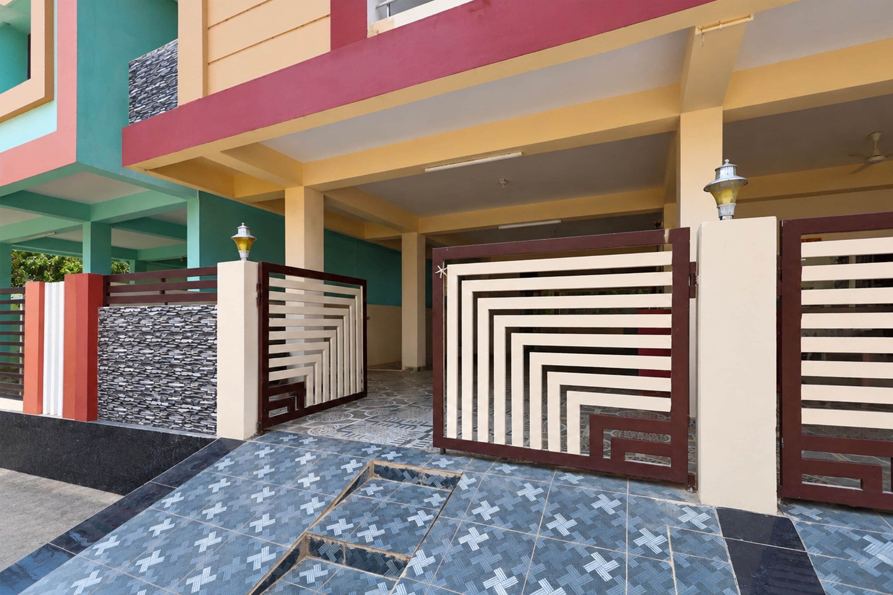 Una entrada de edificio con una reja decorativa, piso de baldosas y pared de piedra.