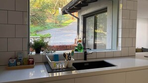 Een keuken met een raam, een spoelbak en een aanrecht met diverse spullen.