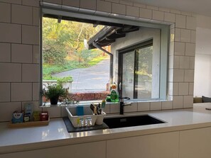 A kitchen with a window, a sink, and a countertop with various items. - Perth Hills Retreat | City Views | Luxury Beds (Gooseberry Hill)