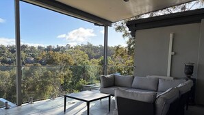Een modern balkon met een bank en een tafel, met uitzicht op een groen landschap.