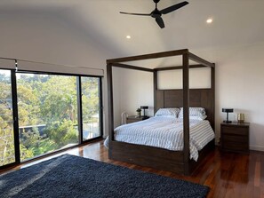A bedroom with a four-poster bed, a large window, and a ceiling fan. - Perth Hills Retreat | City Views | Luxury Beds (Gooseberry Hill)