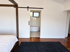 Een slaapkamer met een bed, een zwart tapijt en een wit bad met rozenblaadjes.