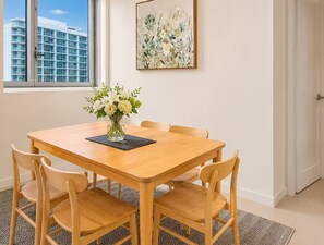 A dining area with a wooden table and chairs, a vase of flowers, and a painting on the wall. - City View 2-bed Apartment Fortitude Valley (Brisbane)