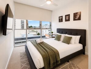 A modern bedroom with a large bed, a ceiling fan, and a city view. - City View 2-bed Apartment Fortitude Valley (Brisbane)