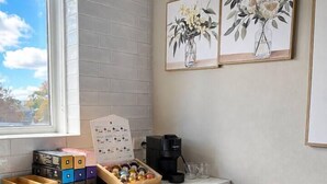 A kitchen counter with a coffee maker, a box of assorted chocolates, and a framed floral artwork on the wall.