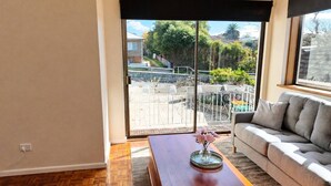 A living room with a sofa, a coffee table, and a view of a balcony with outdoor furniture.
