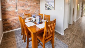 A dining area with a brick wall, wooden table, and chairs.
