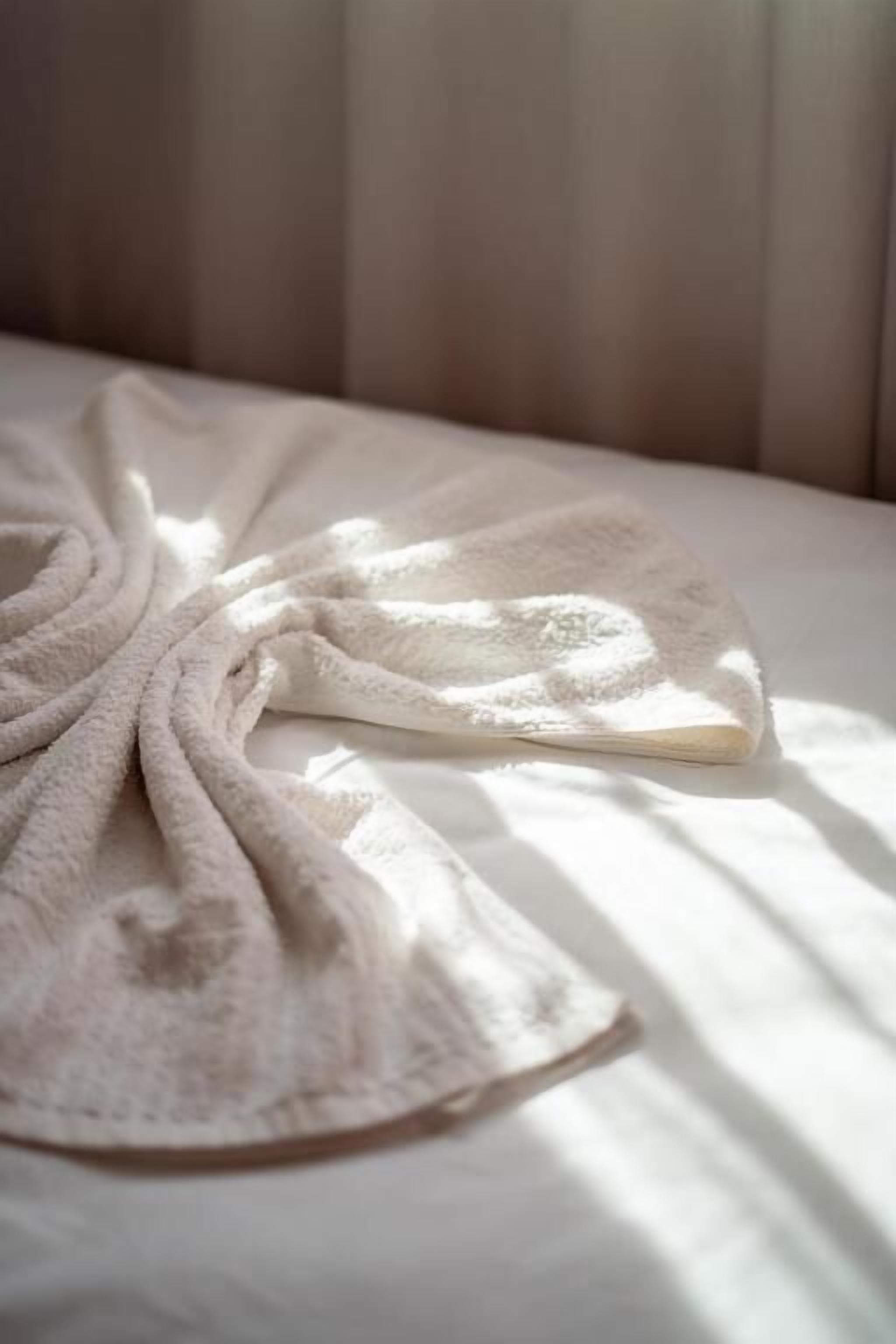 Ein Bett mit weißer Decke und Kissen.