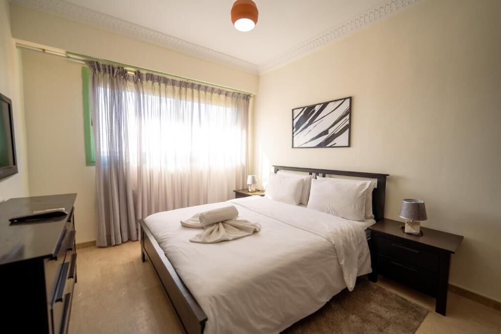 Een hotelkamer met een bed, een bureau, een stoel, een lamp en een schilderij aan de muur.