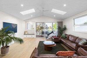 A spacious living area with a large brown leather sofa, a coffee table, and a potted plant. - Oakwood Retreat in Rosebud (Melbourne)