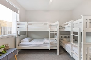 A bunk bed room with white bedding, a desk, and a window. - Oakwood Retreat in Rosebud (Melbourne)