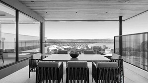 Ein moderner Essbereich mit Tisch und Stühlen, einem großen Fenster und Blick auf eine Stadtlandschaft.